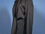 a black suit on a mannequin stand against a blue background