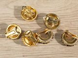 five different types of gold buttons on a wooden surface
