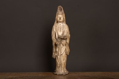 Une statue représentant une femme en robe blanche trône sur une table en bois.