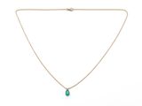 a gold necklace with a green tear pendant on a chain