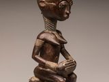 a wooden statue of a woman sitting on a tree stump
