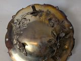 a silver plate with a bird on it sitting on a table