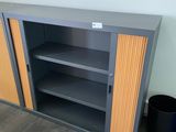 une bibliothèque à deux étagères, avec une poubelle à côté