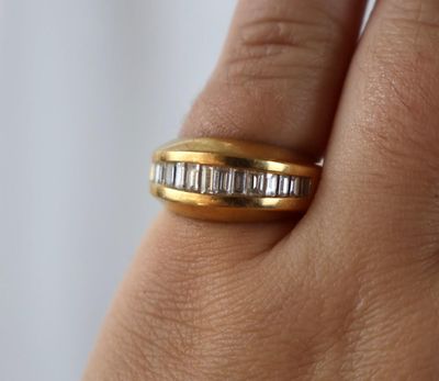 la main d'une femme tenant une bague en or sertie d'une rangée de diamants