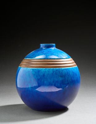 un vase bleu à bord doré et muni d'un couvercle, posé sur une surface grise