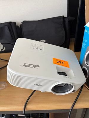 a small projector sitting on a desk next to a speaker