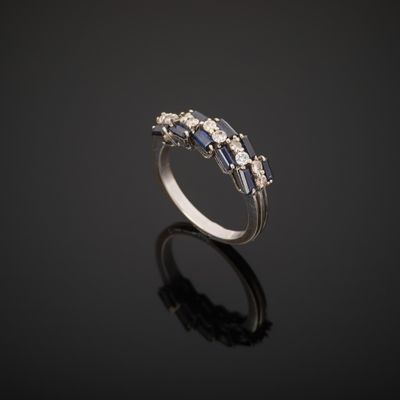 une bague en or blanc sertie de saphirs bleus et de diamants sur un fond noir