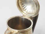 a silver pitcher with a metal lid on a table