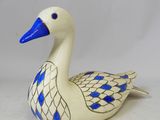 une figurine de canard bleue et blanche posée sur une surface blanche