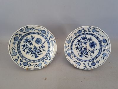 two blue and white plates with floral designs on them sitting on a table