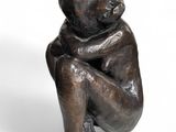bronze statue of a child sitting on his knees on a white background