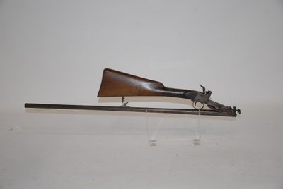an old gun with a wooden barrel on a clear stand