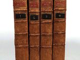three old books are stacked on top of each other on a white surface