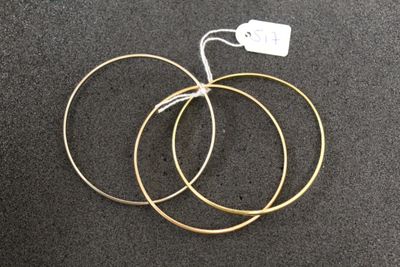 three gold hoop earrings on a black surface with a price tag