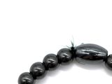 a black bead bracelet with a green bead on it