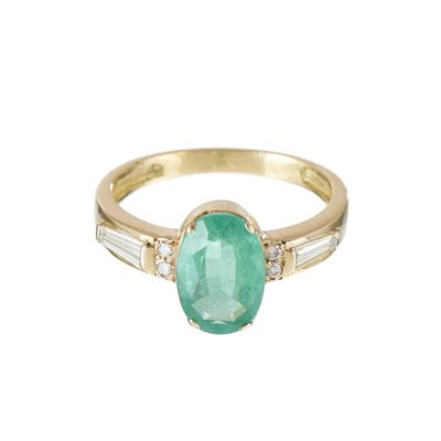 un gros plan d'une bague en or sertie d'une émeraude ovale et de pierres taillées en baguette