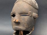 a close up of a clay mask with a tooth sticking out of it ' s mouth