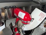 a red mixer sitting on a counter next to other kitchen utensils