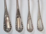 four spoons and a fork are lined up on a white surface