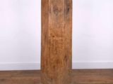 an old wooden column sitting on top of a wooden floor next to a white wall