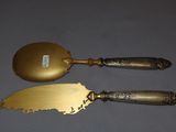 pair of antique brass serving utensils on a gray surface