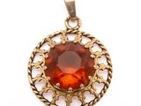 a close up of a pendant with a red stone in it