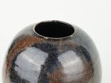 a black and brown vase sitting on a white surface