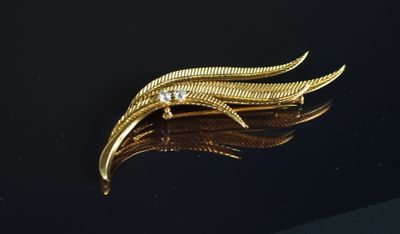 une image représentant une broche en or sertie de diamants sur un fond noir