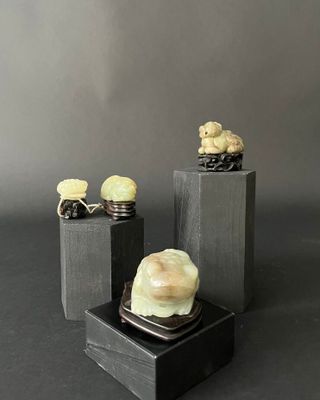 three carved figurines of birds on a black stand on a gray background