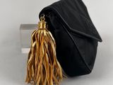 the small black bag has a tassel hanging from it ' s handle