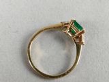 a close up of a gold ring with an emerald stone