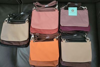 several purses are lined up on a black leather couch
