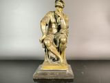 bronze statue of a man sitting on a stool with a dog
