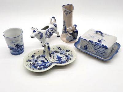 Plusieurs pièces de poterie bleue et blanche sont exposées sur un fond blanc