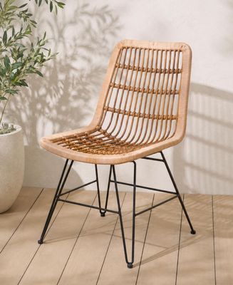 La chaise en rotin est posée sur un parquet, à côté d'une plante en pot.