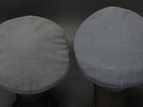 pair of round foot stools with grey cushions on top of them