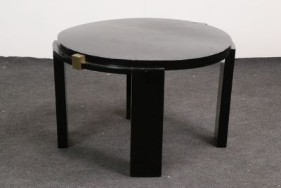 une table noire avec un plateau rond en verre, posée sur un sol recouvert de moquette