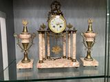 a glass shelf with a clock and two vases on it
