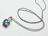une chaîne en argent à laquelle est accroché un pendentif bleu et blanc