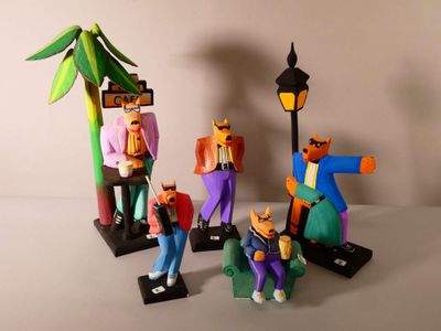 Plusieurs figurines représentant des personnages vêtus de habits colorés sont disposées près d'un lampadaire.