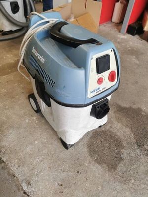 a blue and white vacuum sitting in a garage