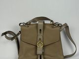 le petit sac beige est posé sur une surface blanche