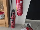 un extincteur posé à côté d'une lance à incendie, au sol