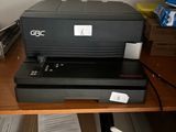 une imprimante posée sur un bureau, à côté d'une pile de papiers