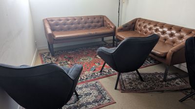 un salon avec un canapé, des fauteuils et un tapis