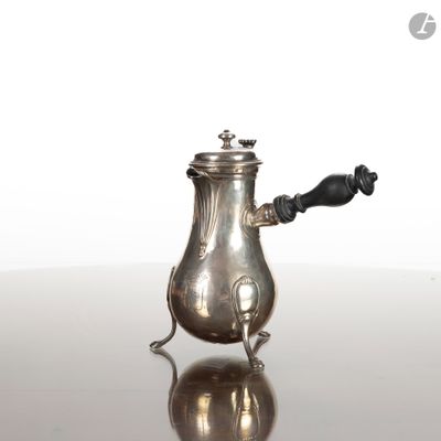 une théière en argent posée sur une table, avec une anse noire