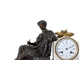 a statue of a woman sitting on a table next to a clock