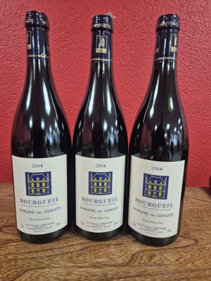 trois bouteilles de vin sont posées sur une table devant un mur rouge
