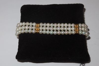 two rows of white pearls with gold accents on a black velvet bag