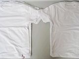 two white t - shirts sitting on top of a table next to each other